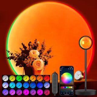 A sunset projection lamp casts a vivid orange and green circular glow on a wall, with a floral arrangement in front. A smartphone with a color wheel app, a remote control, and a clock are also visible. Sixteen small color options are shown at the bottom.